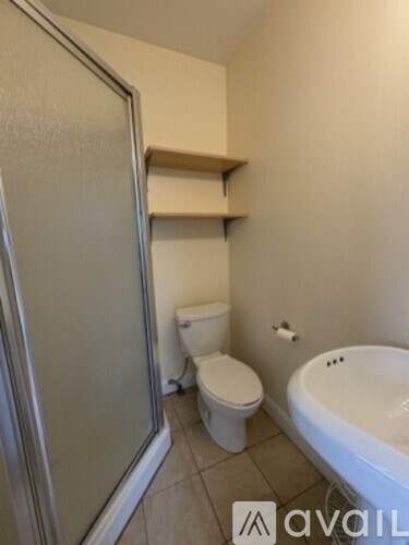 A bathroom with a toilet, tub, and a shower door.