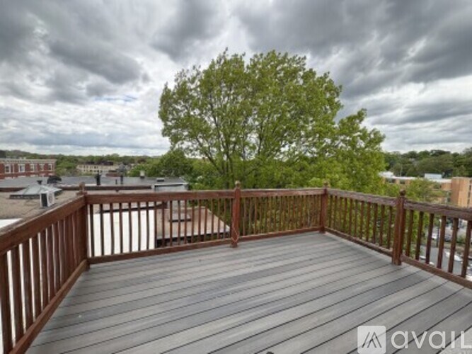 A wooden deck with a railing and a tree in the background.