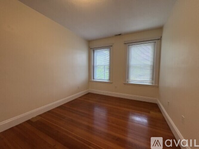 A room with wooden floors and two windows.