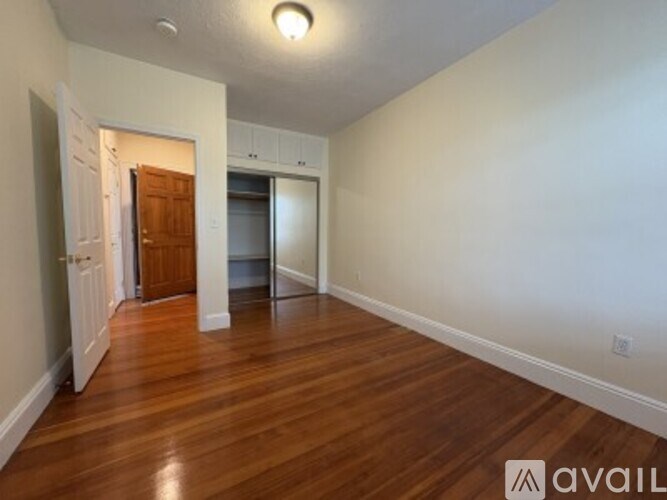 A room with wooden floors and a door leading to another room.