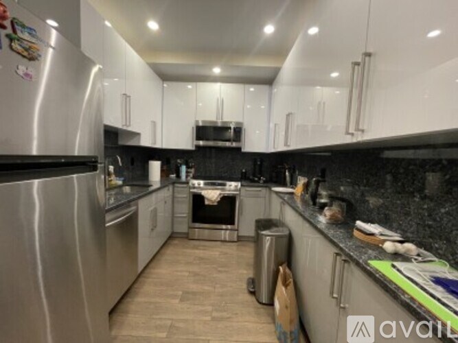 A kitchen with a stainless steel refrigerator and white cabinets.