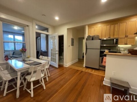 A kitchen with wooden floors and white chairs.