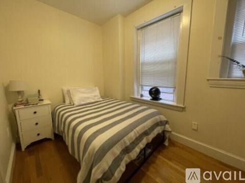 A bedroom with a bed, nightstand, and window.