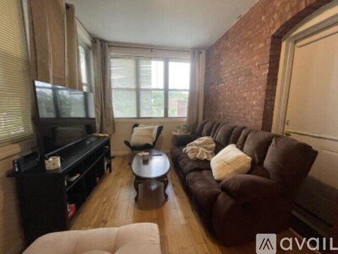 A living room with a brown couch, a coffee table, and a television.