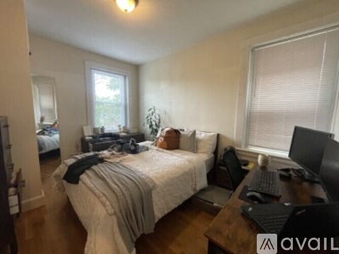 A bedroom with a bed, desk, and window.