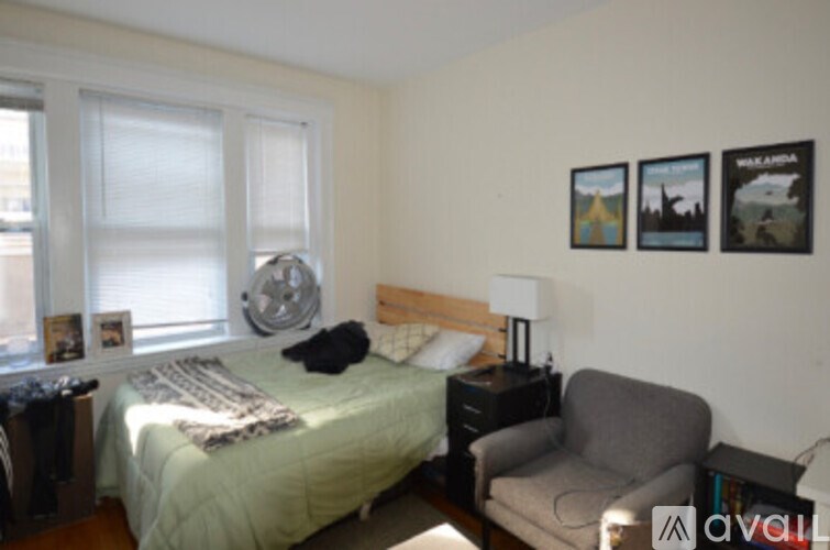 A bedroom with a bed, a chair, and pictures on the wall.