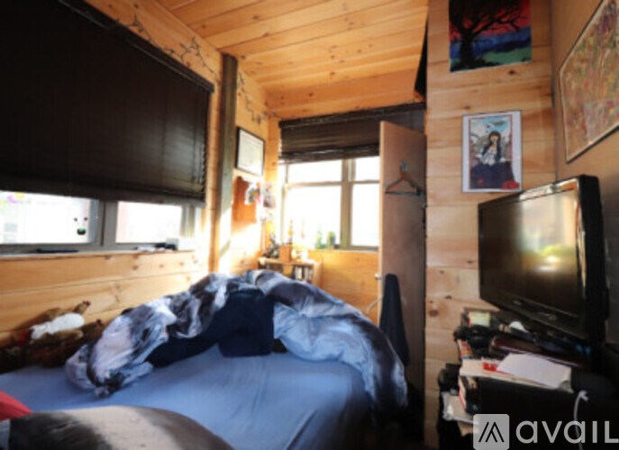 A bedroom with a bed, a desk with a computer, and a TV.