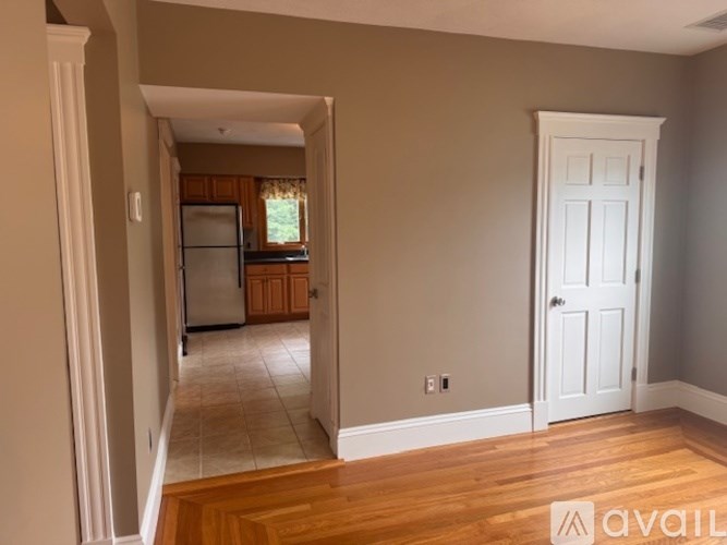 A kitchen with a refrigerator and wooden floors.