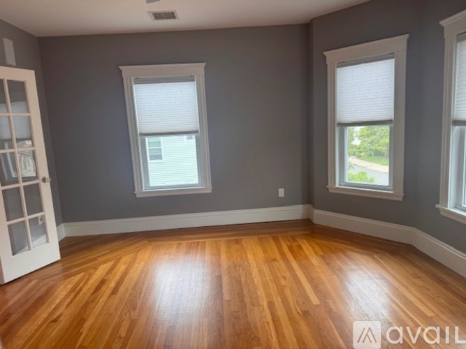 A room with wooden floors and two windows.