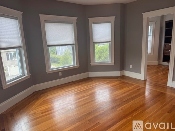 A room with wooden floors and three windows.