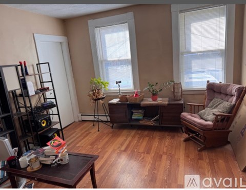 A living room with a brown sofa, a wooden coffee table, and a bookshelf with various items.