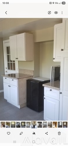 A kitchen with white cabinets and a black fridge.