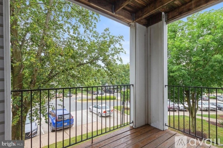 A balcony with a black railing and a view of a street with cars.