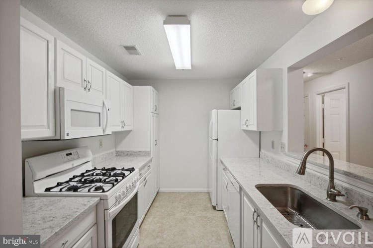 A kitchen with white cabinets and a marble countertop.