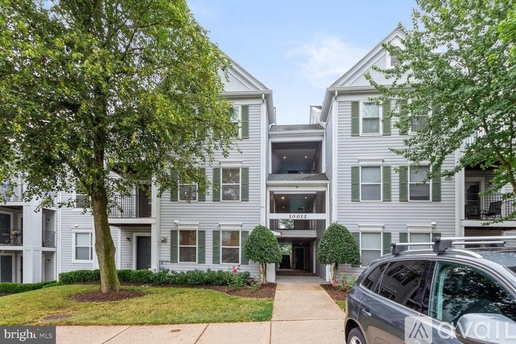 A grey apartment building with a tree in front of it.