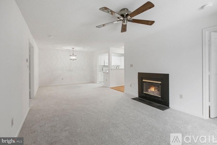A living room with a fireplace and a ceiling fan.