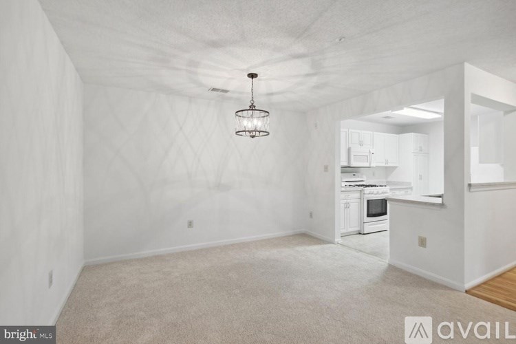 A spacious, empty room with a chandelier hanging from the ceiling.
