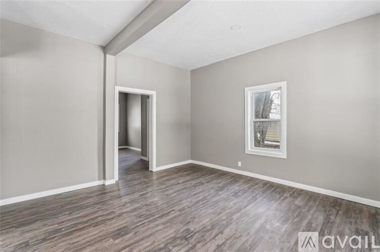 A room with wooden flooring and a picture frame on the wall.