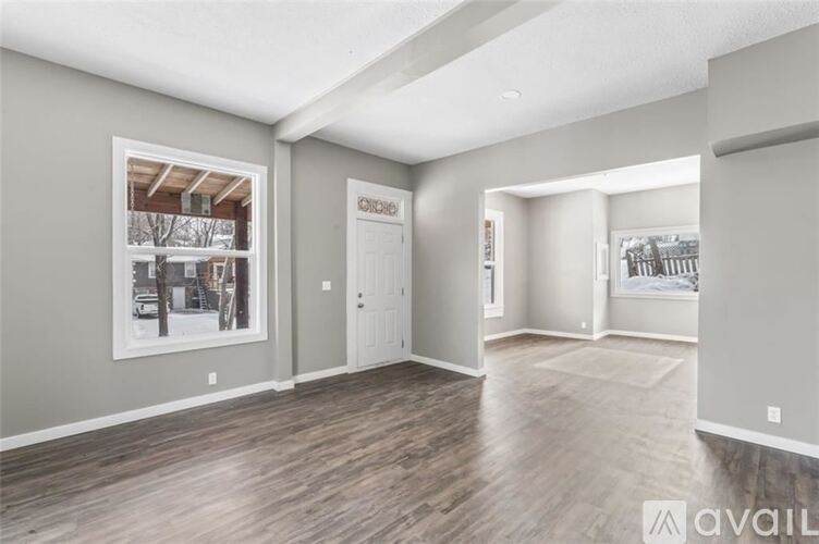 A spacious room with wood flooring and a large window showing an outdoor view.