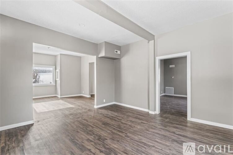 A spacious room with wood flooring and white walls.