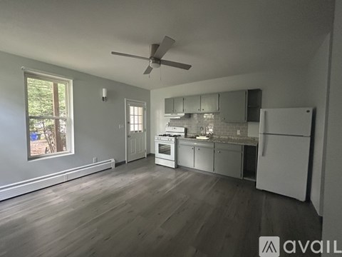 A spacious kitchen with white appliances and wooden floors.