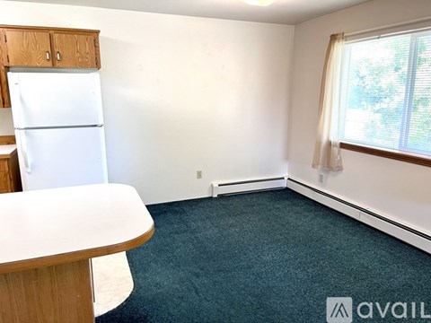 A kitchen area with a white refrigerator and a round table.