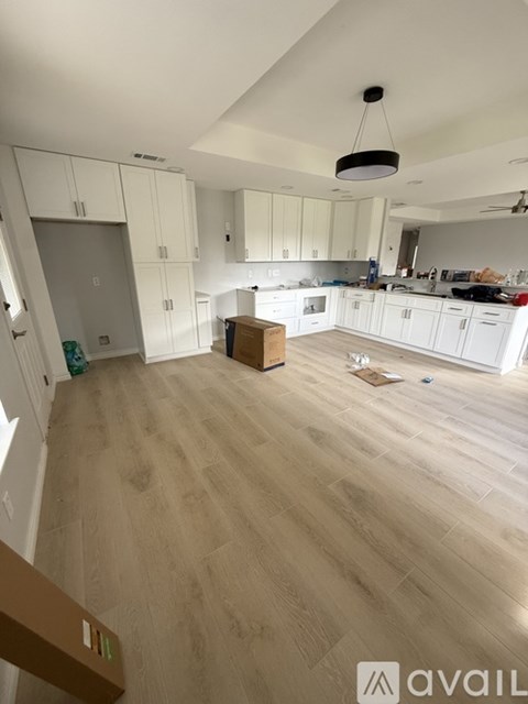 A kitchen with white cabinets and a wooden floor.
