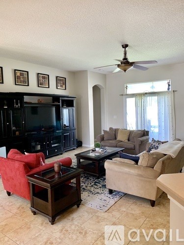A living room with a red chair and a black entertainment center.