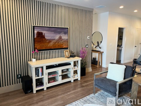 A living room with a television and a striped wallpaper.