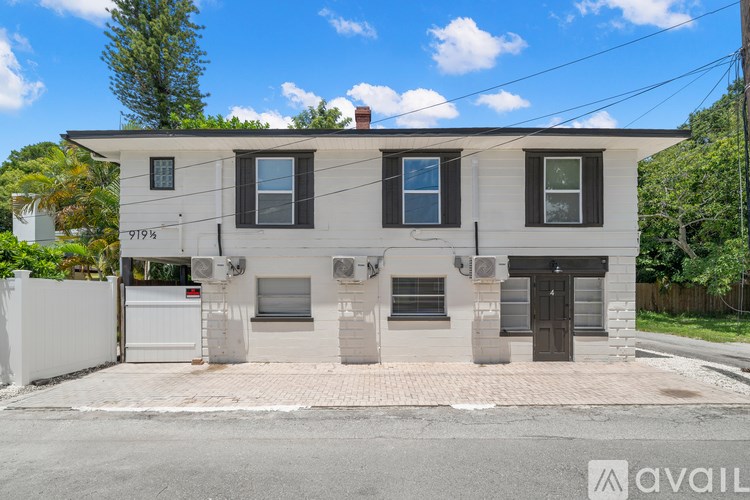 A two-story house with a white exterior and a black door is for sale.