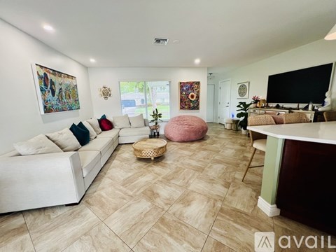 A living room with a white couch and a pink bean bag chair.