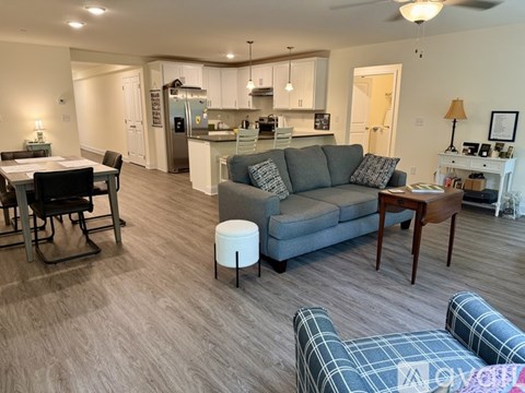 A living room with a grey couch and a dining table with chairs.