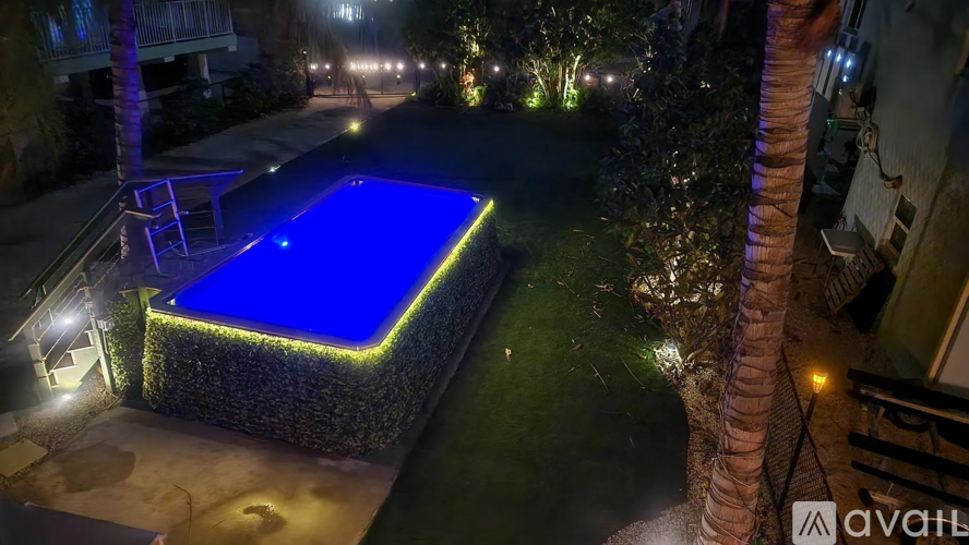 A swimming pool lit up at night with a stone wall surrounding it.