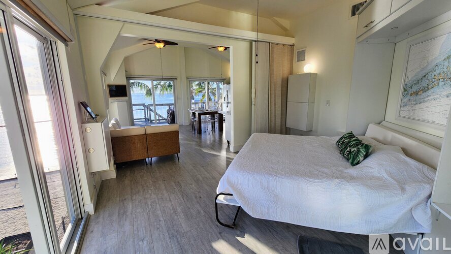 A bedroom with a large bed and a balcony overlooking the water.