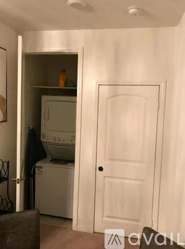 A white door is open to a small kitchen with a washing machine and a microwave.