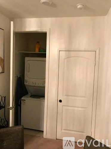 A white door is open to a small kitchen with a washing machine and a microwave.