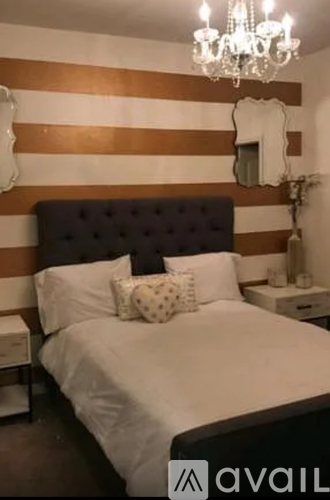 A bedroom with a bed, a chandelier, and a mirror on the wall.