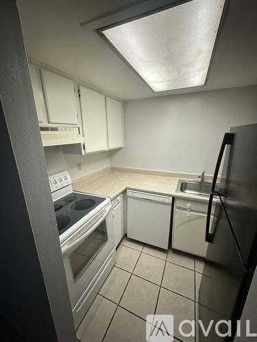 A kitchen with white cabinets and a black fridge.