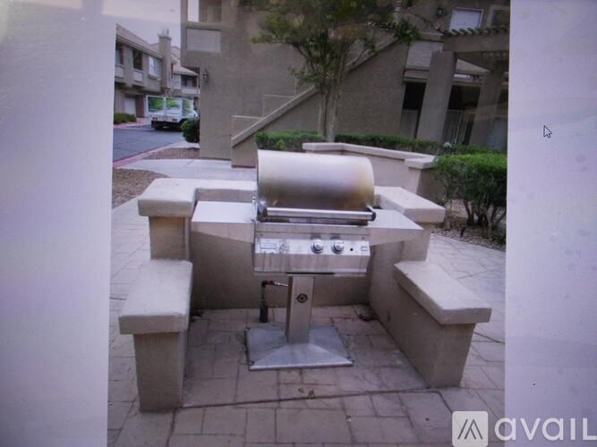 A BBQ grill is in the middle of a concrete patio.