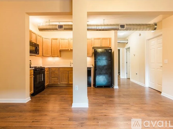 A kitchen with wooden cabinets and a black fridge is available.