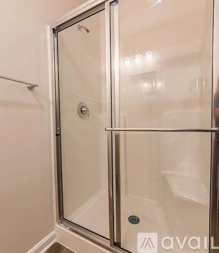 A glass shower door with a silver handle and a silver handle plate.