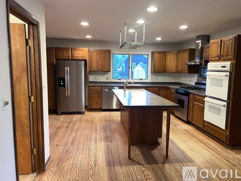 A kitchen with wooden cabinets and a large island in the middle.