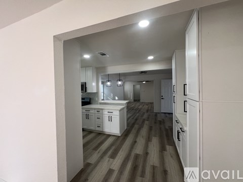 A kitchen with white cabinets and a wooden floor.