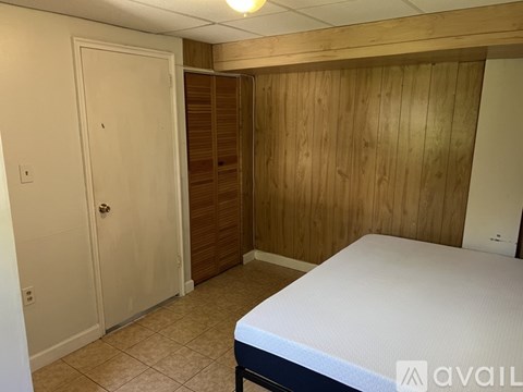 A bedroom with a bed, wooden wall, and a door.