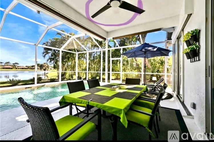 A table with a green tablecloth is set up on a balcony with a pool in the background.