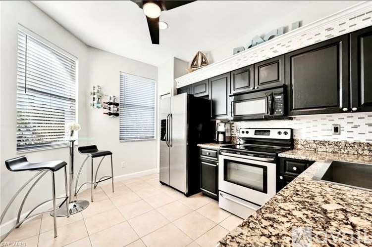 A kitchen with black cabinets and granite countertops.