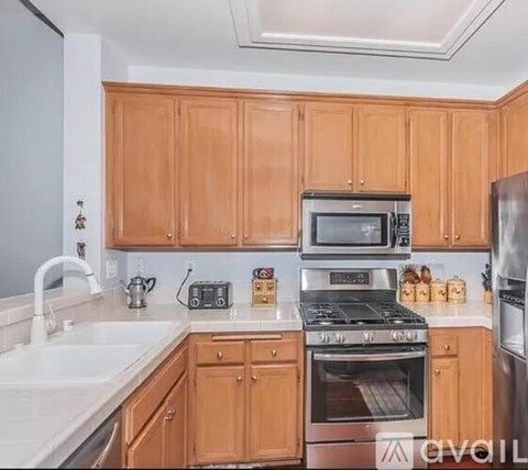A kitchen with wooden cabinets and a stainless steel refrigerator.