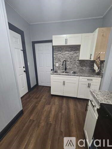 A kitchen with white cabinets and a stone backsplash.