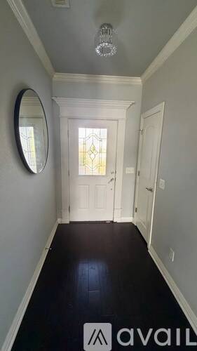 A hallway with a round mirror and a chandelier.