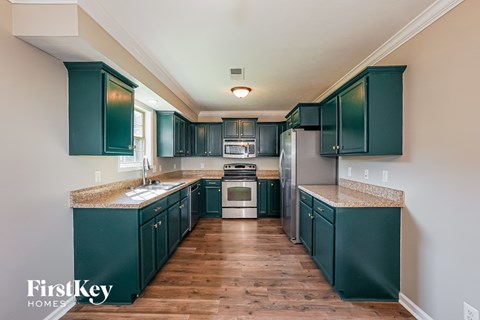 A kitchen with dark green cabinets and a wooden floor.